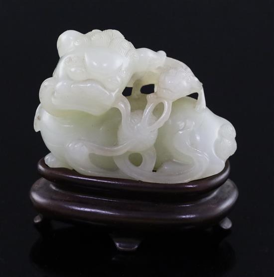 A Chinese pale celadon jade figure of a lion dog and cub, 18th/19th century, L. 6cm, wood stand